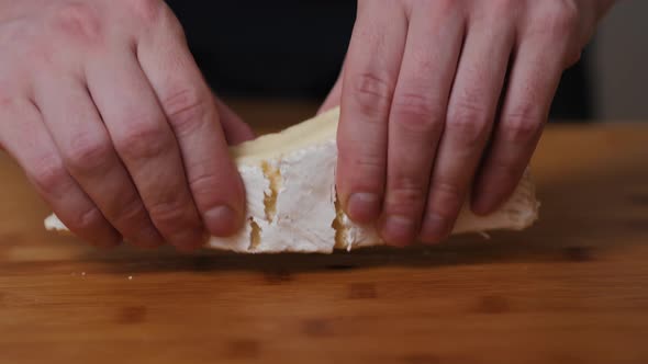 People Cut Cheese with a Knife on Old Wooden Table Break Brie Close Up Macro Cheese