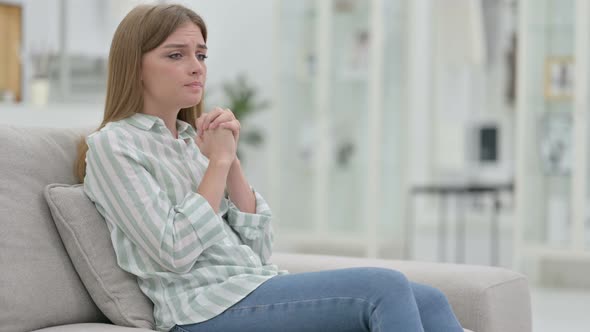 Worried Young Woman Sitting on Sofa and Thinking 