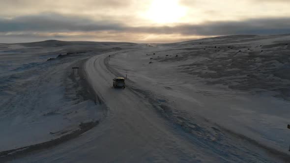 Aerial View, Car on Icy Road in Highland of Iceland With Stunning Sky on Horizon ,  Cinematic Drone