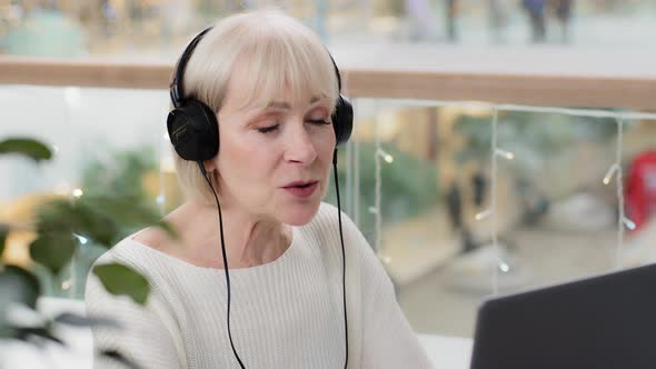 Successful Professional Businesswoman in Headphones Communicates Via Video Call on Laptop Mature