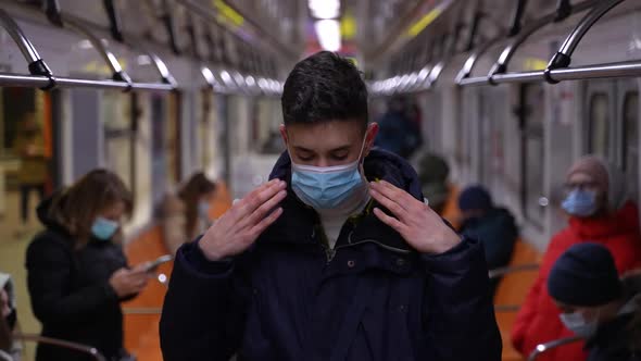 Tall Teen Boy Putting on Face Mask in Subway Train