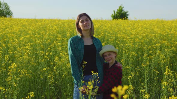 Mother Woman Stands in Yellow Flowering Rapeseed Embrace Little Daughter