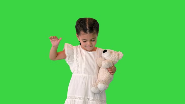 Cute Smiling Little Child Girl with Her Favorite Teddy Bear Toy Walking on a Green Screen Chroma Key