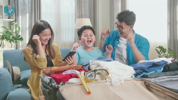 Asian Family Booking Hotel On Smartphone And Celebrating For A New Journey