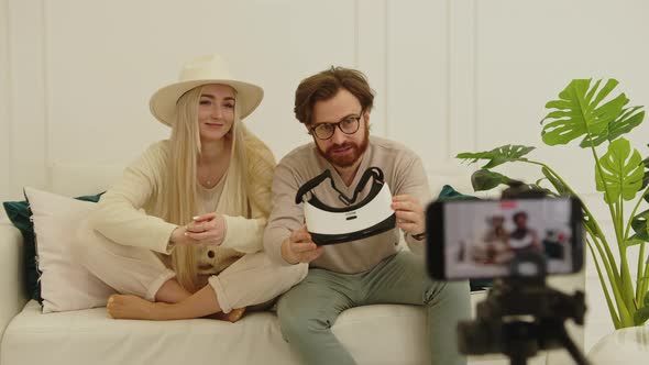 Cheerful European Influencers Creating a New Video While Sitting on a White Couch in Their Modern