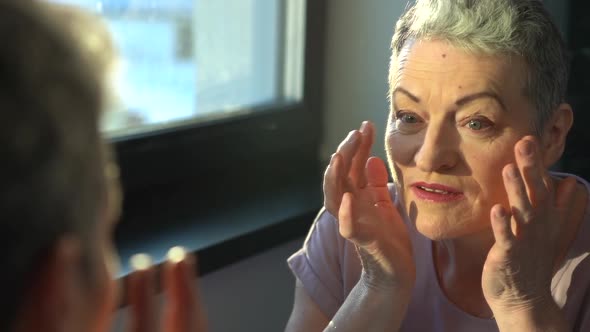 Senior Female Looking at Sagging Skin Face in Mirror Old Age Appearance