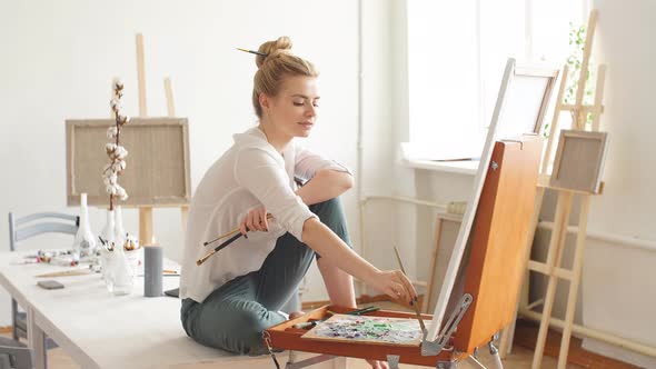 Talented Artist Sitting on the Table and Drawing Her Picture at Home