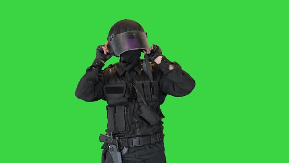 Police Officer in Full Protection Riot Gear Putting on Helmet on a Green Screen Chroma Key