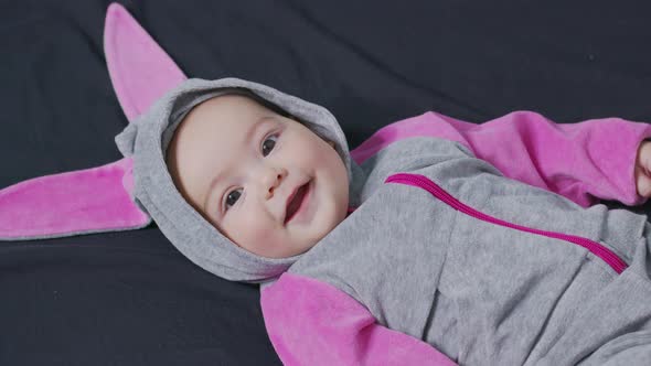 Cute Baby Smiling and Looking in the Camera Close Up. Little Kid in Bunny Costume, Top View.