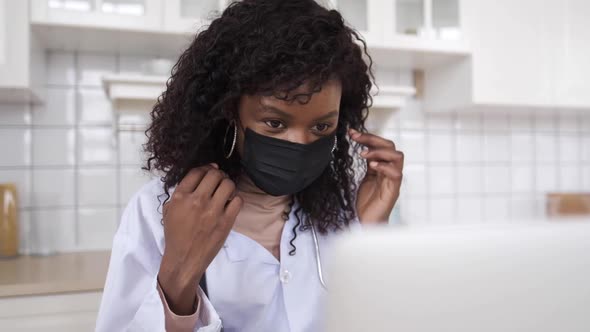 A Black Female Doctor Teaches at Home Using a Video Call Application on Her Computer To Show How To