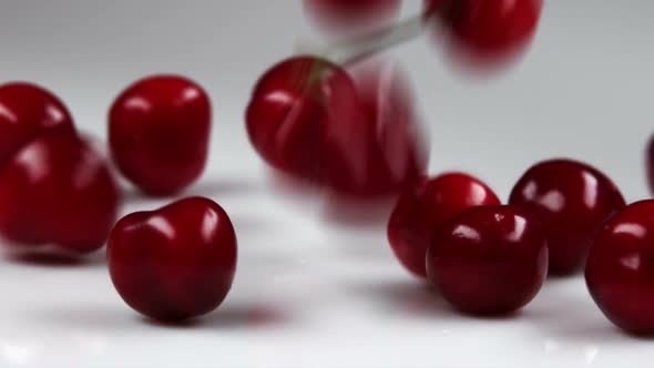 Red cherries being dropped onto a table.