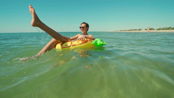 Happy Smiling Young Woman in Sunglasses Swimming on Inflatable Pineapple Floating Ring in Sea Water