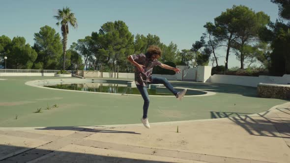 Slow motion shot of young man jumping and playing air guitar
