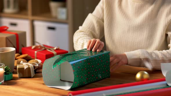 Woman Wrapping Christmas Gift Into Paper at Home