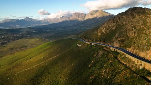 Drone in crane motion above Hermanus highway through lush rich hillside