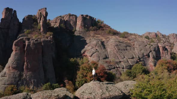 Aerial video with a woman at the edge of stunning rock formation