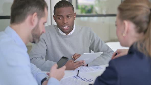 Male and Female Businessperson Using Tablet and Smartphone During Discussion