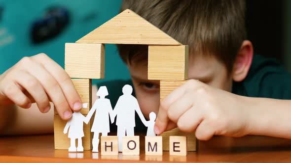 A happy child plays with blocks built a house and made the inscription home. A Caucasian preschooler