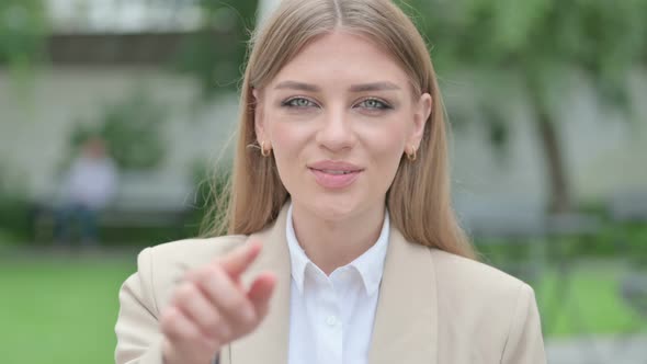 Outdoor Portrait of Young Businesswoman Pointing and Inviting