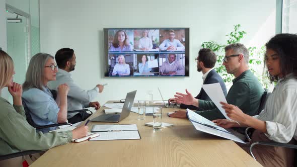 Diverse Employees on Online Conference Video Call on Tv Screen in Meeting Room