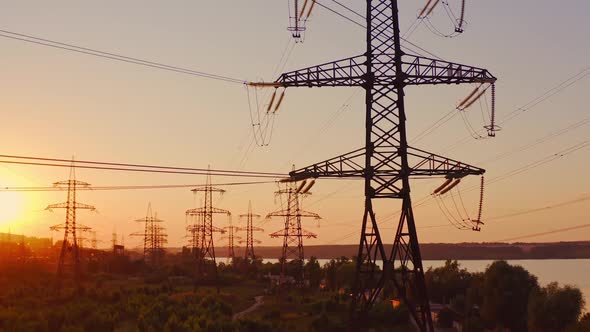 Transmission lines near the river. High-voltage electric towers at sunset.