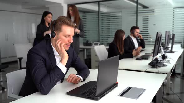 An Attractive Young Man Working in a Call Center with His Colleagues