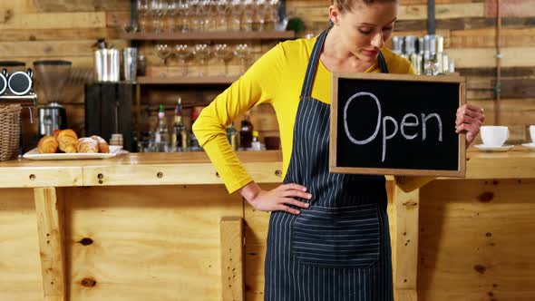 Waitress showing slate with open sign in cafe