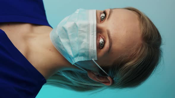 Blonde Caucasian Nurse with a Surgical Mask Looking at the Camera Vertical Video Closeup Studio Shot