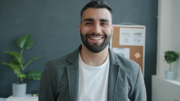 Slow Motion Portrait of Cheerful Goodlooking Entrepreneur Standing in Office Smiling