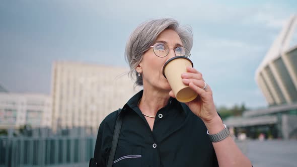 Close Up Outdoor Portrait of a Business Lady During Lunchtime Mature Woman Drinks Coffee and Holds a