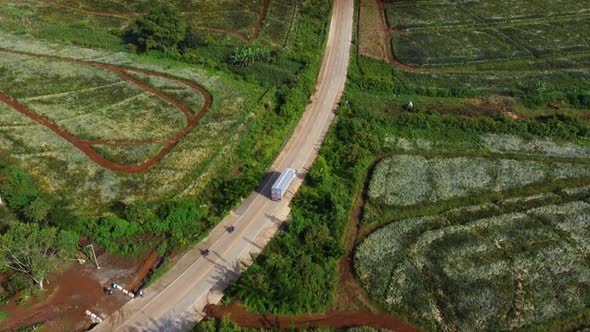 Aerial shot of Delivery truck on a Country Road and Large Plantation