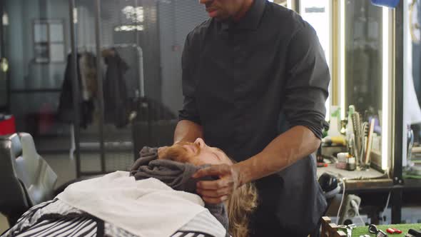 Barber Giving Facial Massage with Towel to Male Client