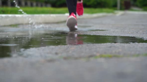 Legs of a Runner in Sneakers. Sports Woman Jogging Outdoors, Stepping Into Muddy Puddle. Single