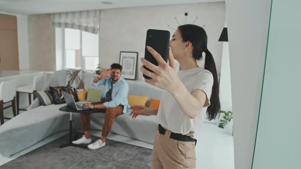 Young Married Couple Video Calling On Smartphone At Home