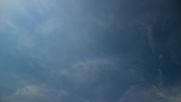 Time Lapse Of Looking Up At Wisps Of Clouds Going Past Against Blue Sky. Tracking  Pan Right Shot