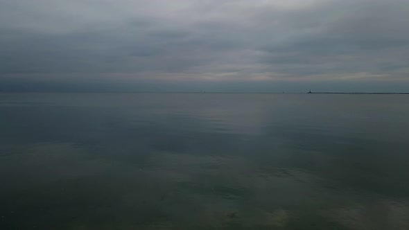 Slowmotion aerial shot of Seagull flies above calm sea at cloudy autumn day