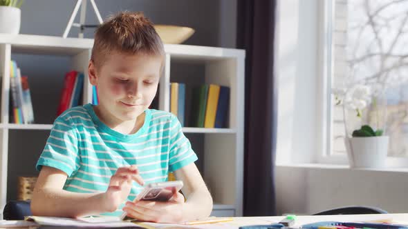 Boy is Doing  Homework at the Table. Cute Child is Learning at Home.