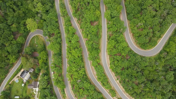 Aerial time lapse of numerous vehicles driving along a curvy mountain road with several hairpin turn