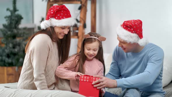 Amazed Little Cute Girl Feeling Happy Getting Gift Box From Parents Celebrating Christmas Holiday