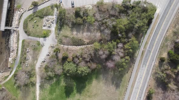 Birdseye drone flight over suburban coastal park with a boat launch, tables and a tidal wetland near