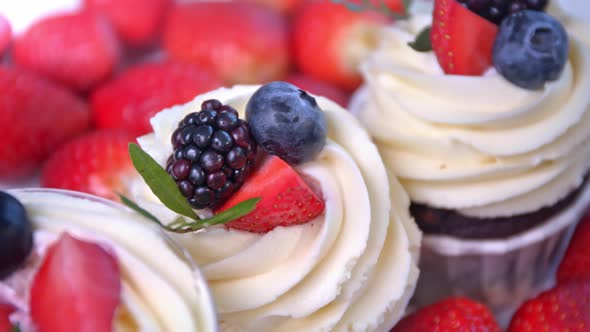 Few Delicious Fruit Cupcake with White Whipped Cream and Slices of Fresh Red and Black Berries