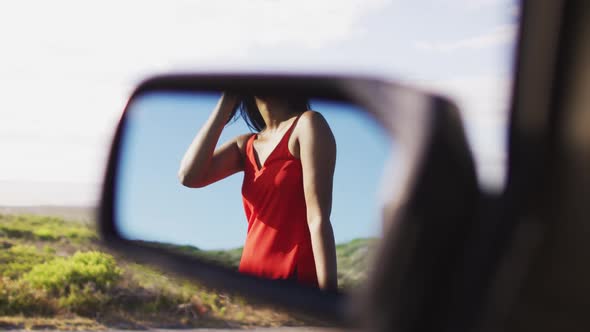 Reflection of african american woman standing on the road from side rear view mirror of the car