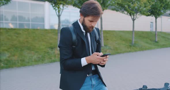 Stylish Guy Stopping on His Bike and Writing Messege on His Smartphone