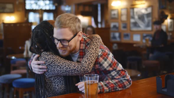 Multiethnic Couple Meeting and Hugging in Modern Beer Pub