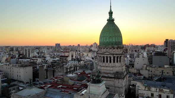 Aerial pan right of Argentine Congress Palace green bronze dome surrounded by buildings at sunset, B