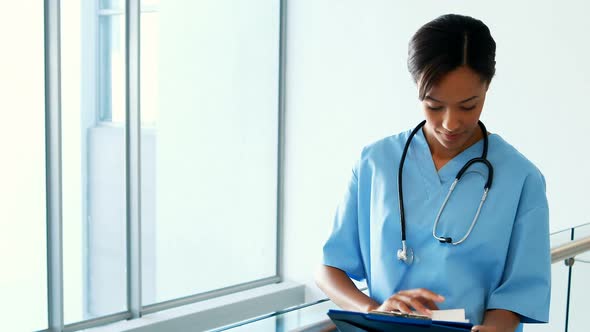 Female doctor looking at clipboard in corridor