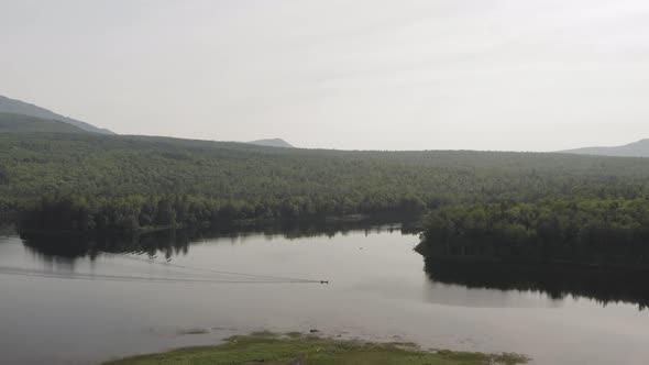 Wide Lakeview aerial flying over fishing boat in the heart of nature