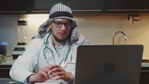 Arabic Doctor's Remote Work Sitting at the Computer and Speaking with Patient