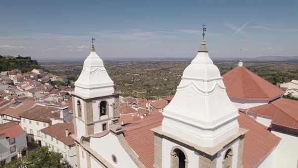 Aerial circling around bell towers of Santa Maria da Devesa church and old castle in background