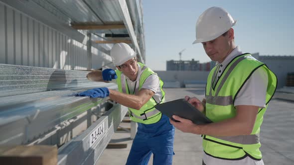 Caucasian and Middle Eastern Workers Inspecting Delivered Cargo at Warehouse Storage Outdoors on